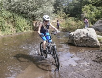 Una ciclista alle prese con l'attraversamento di un corso d'acqua